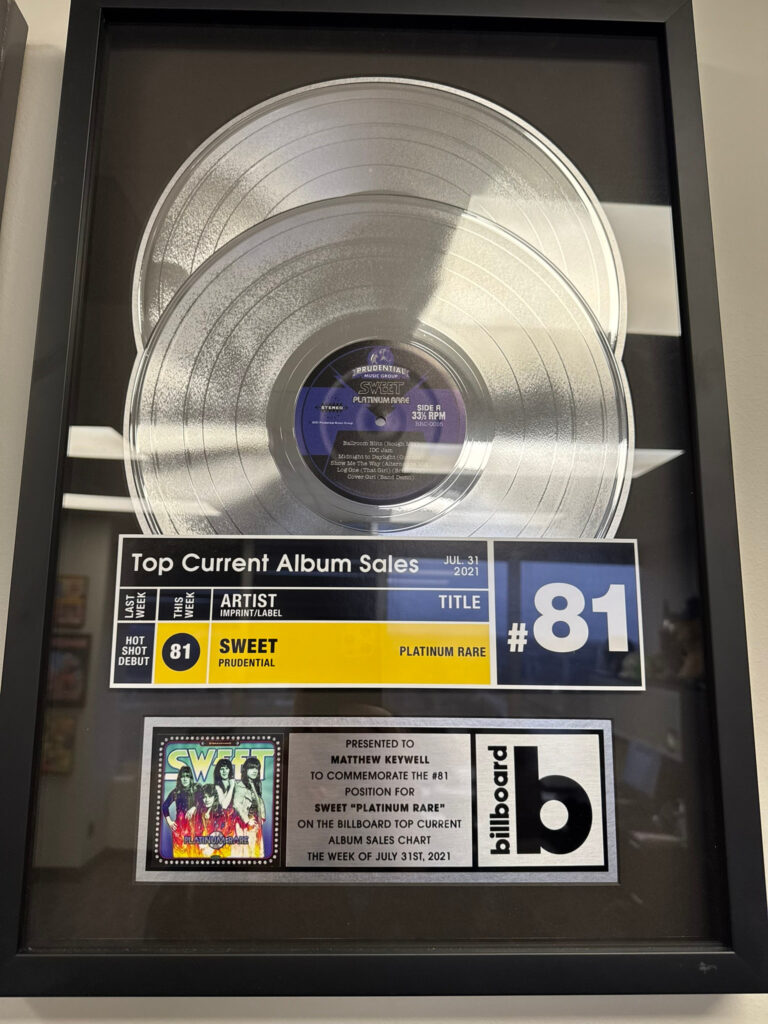 Framed Billboard album sales award with a platinum record