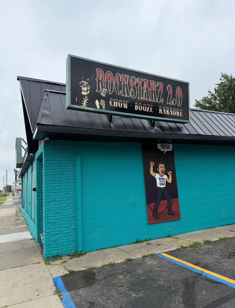 Teal building with a rock-themed sign and mural