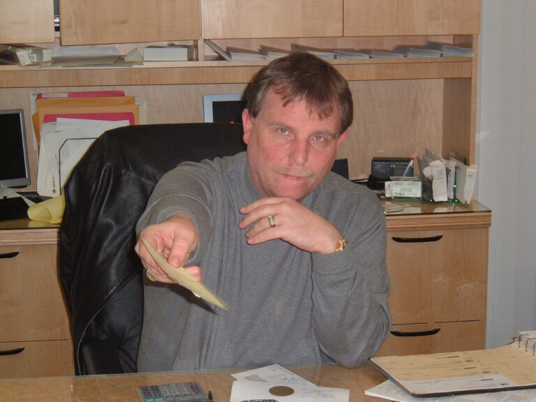 A man at a desk holding out cash