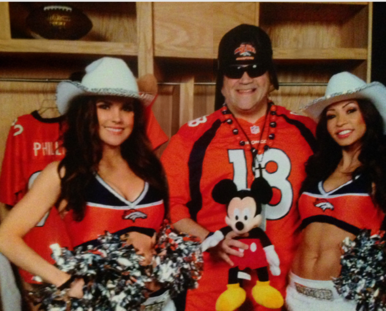 A man in a football jersey and mask with two cheerleaders