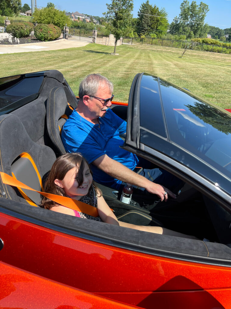 A man and a child in an orange convertible