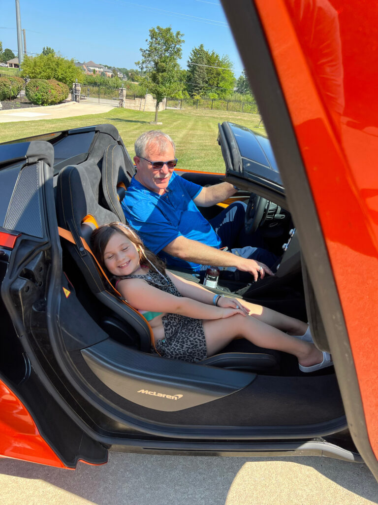 A man and a child in an orange sports car